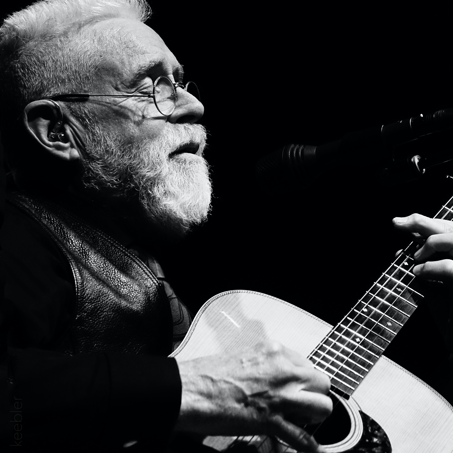 Bruce Cockburn playing guitar in a black and white photo.