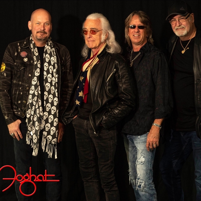 Four members of the band Foghat standing together with a black background.