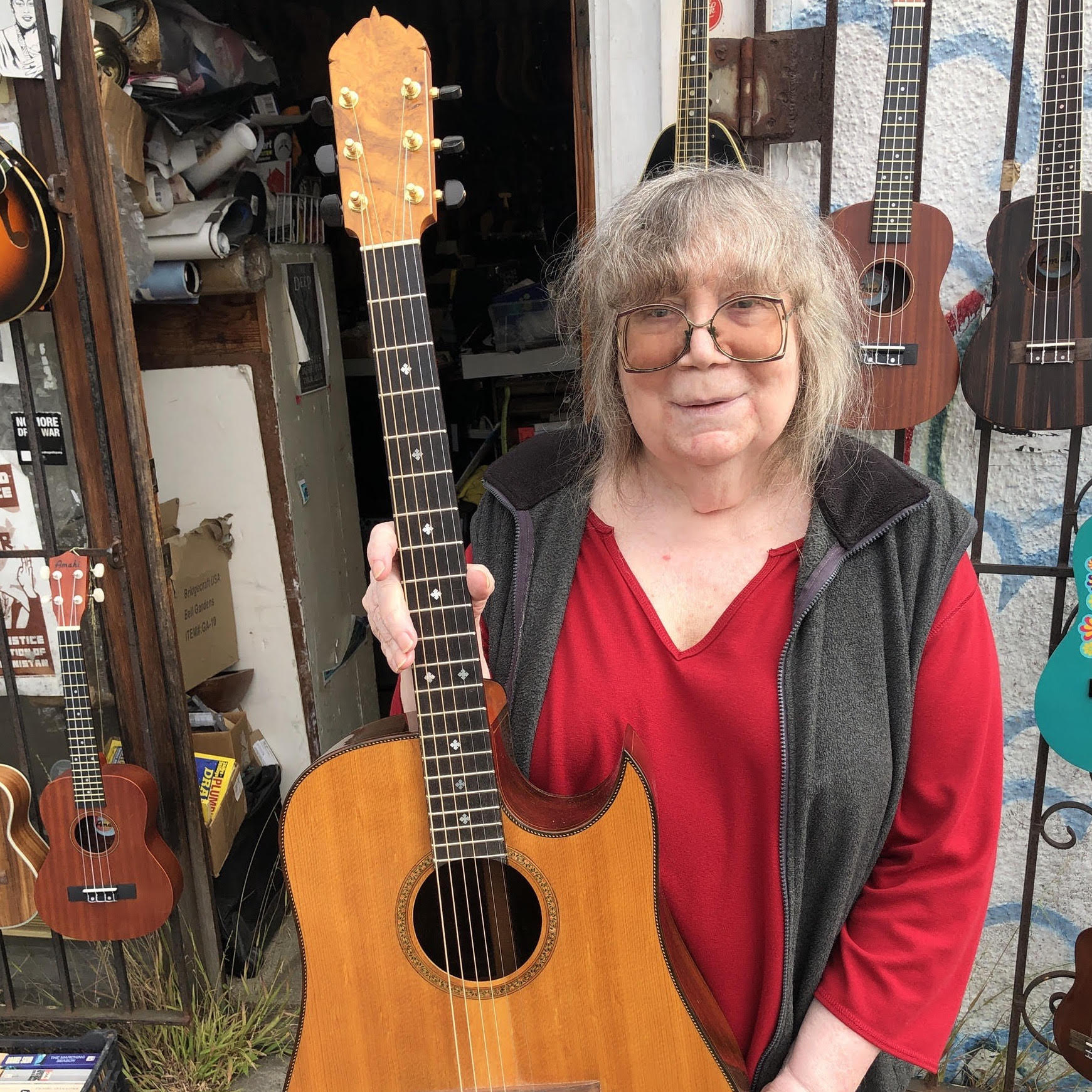 Local musician, Lynda Carson, standing in a doorway holding an acoustic guitar.