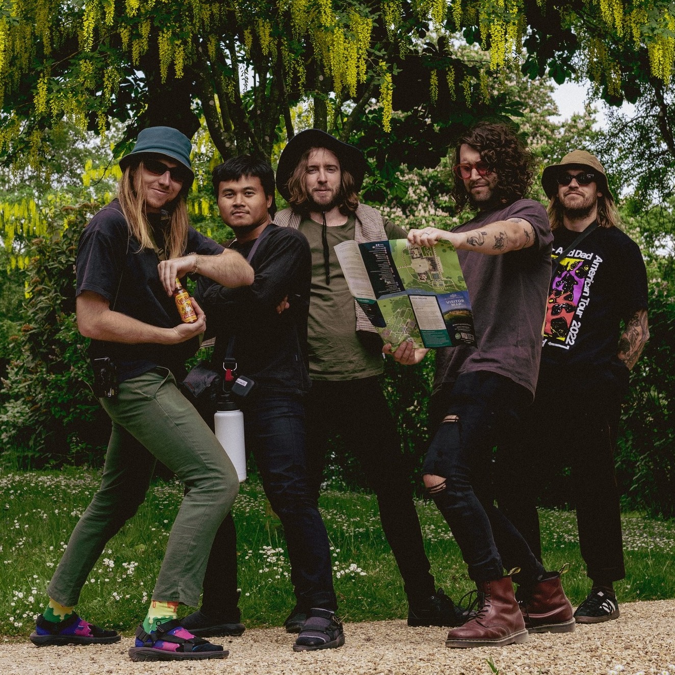 Members of the band standing in a park in front of a tree.