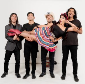 Five members of band standing in front of a white background.