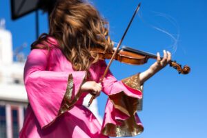 Amanda Shaw, wearing a pink dress, playing the fiddle