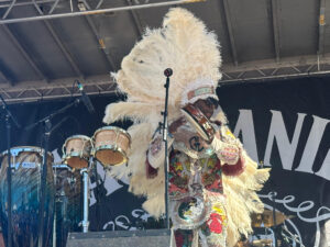 A performer in a full headdress performing on stage as part of The Rumble