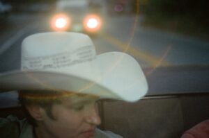 Musician Adrienne Lenker wearing a cowboy hat sitting in a car