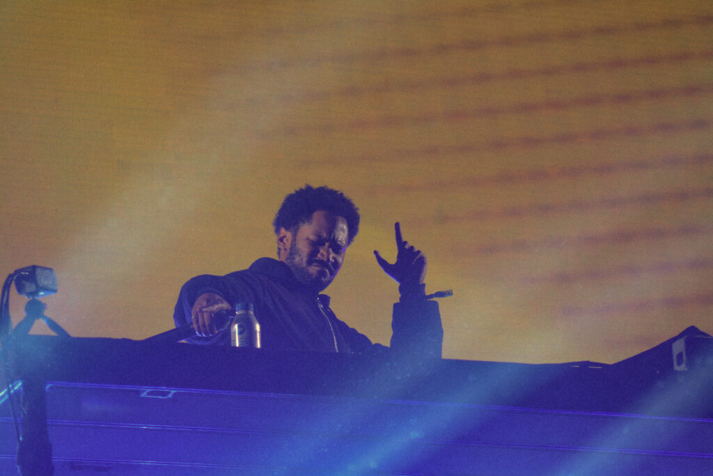 Musician at his instrument one hand in the hair at night on an outdoor stage