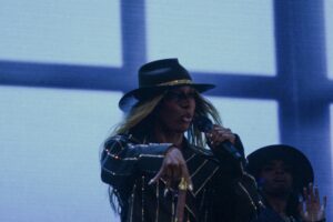 Woman singing into a microphone and dancing on stage