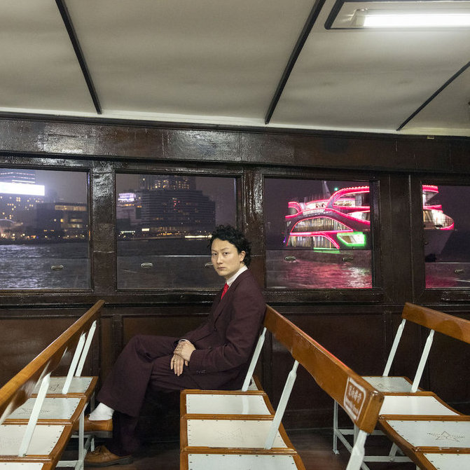 Bolis Pupul sitting down in a room with a boat in the background.