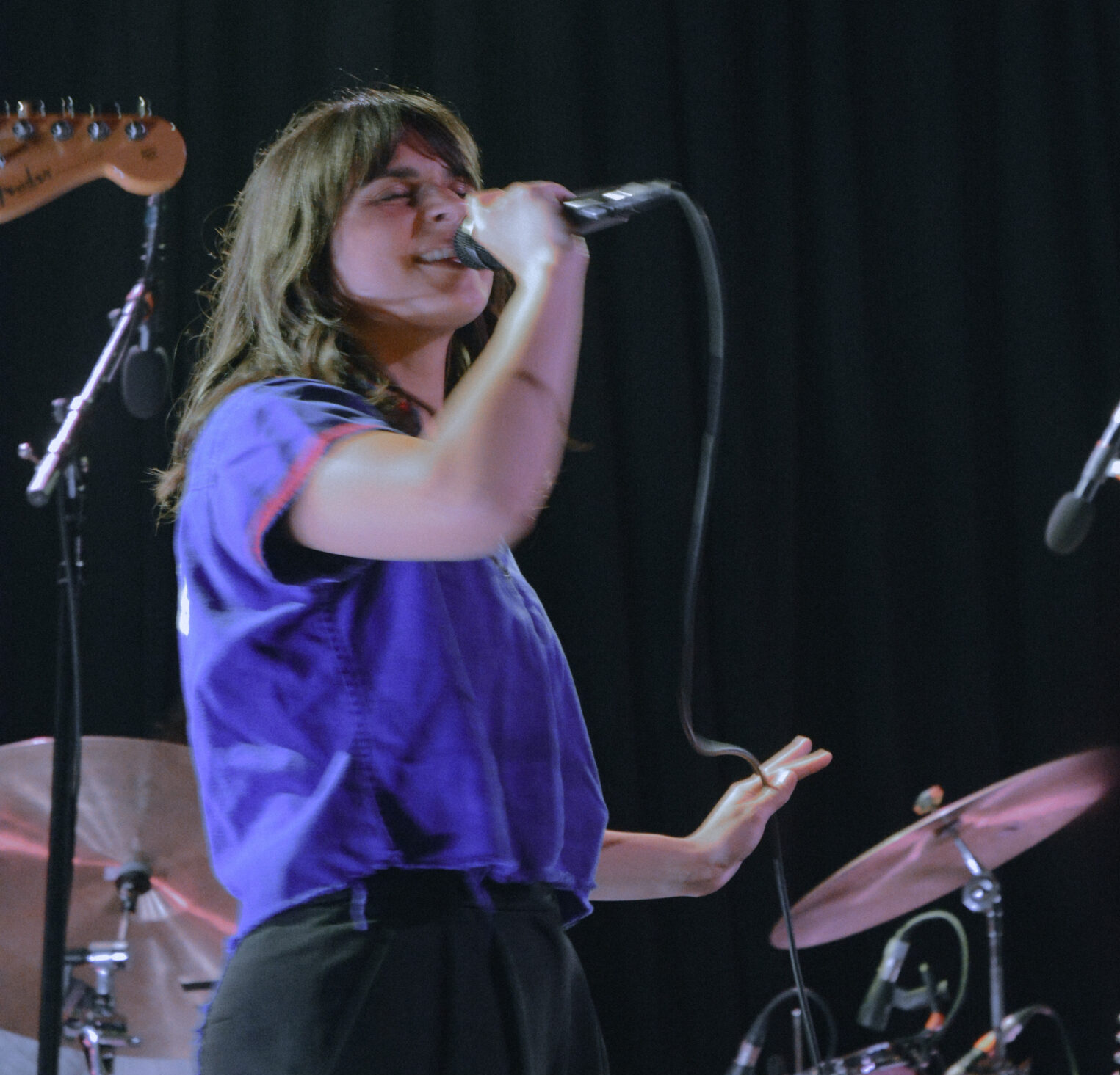 Woman singing into a microphone on stage