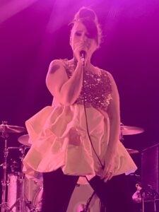 Singer performing on stage in a purple glow of lights