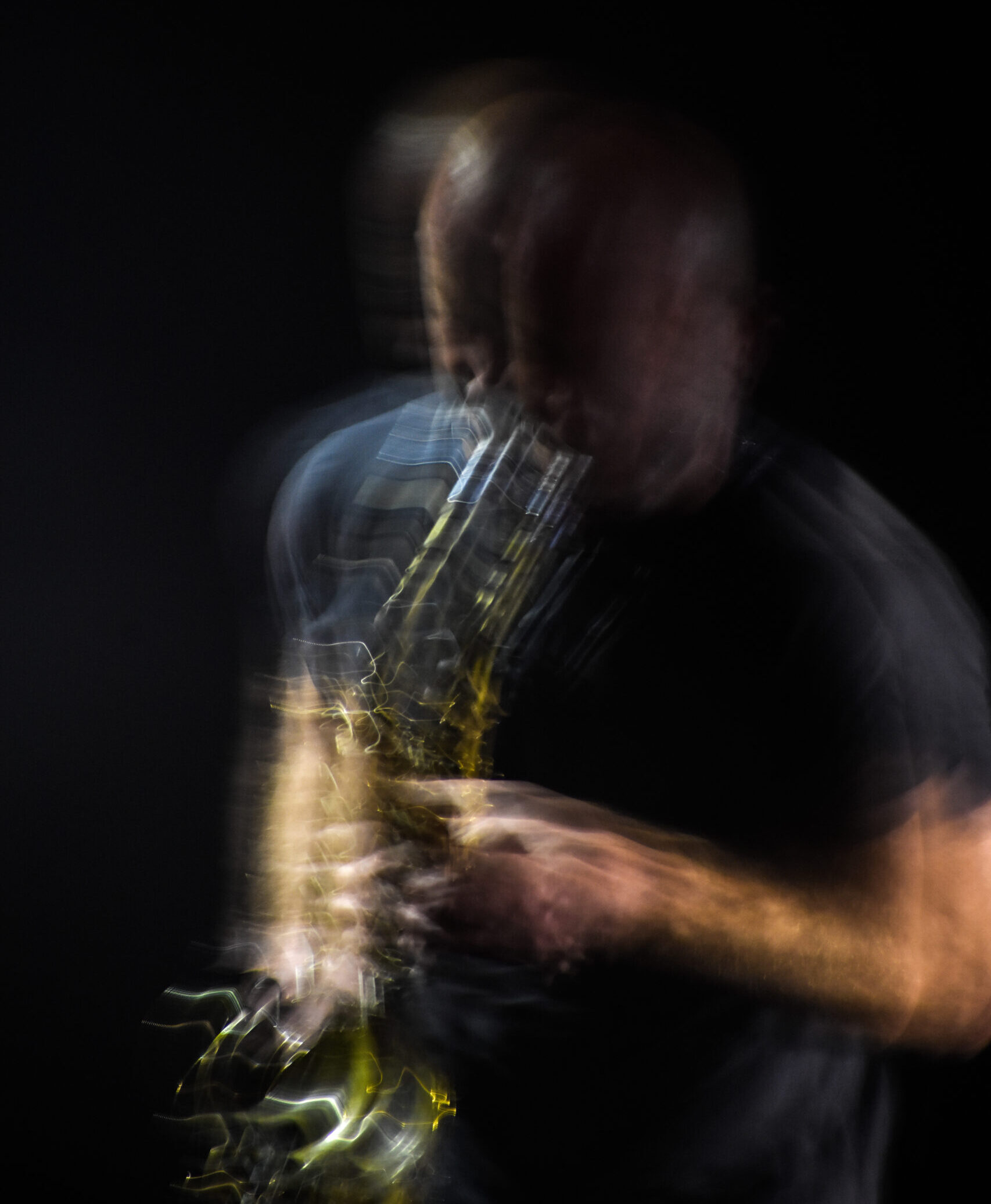 Man playing the saxophone on stage blurring in moition