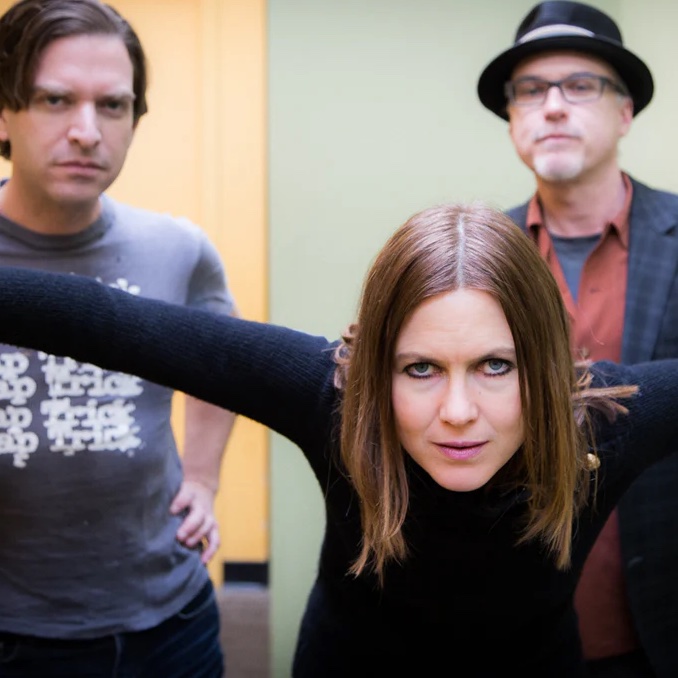 All three members standing together in a room.