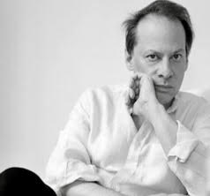 Black and white photo of a man sitting with one hand resting against his chin.