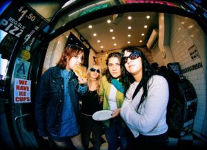 The four members of rock band Lime Garden in the doorway of a NY pizza place eating a slice.