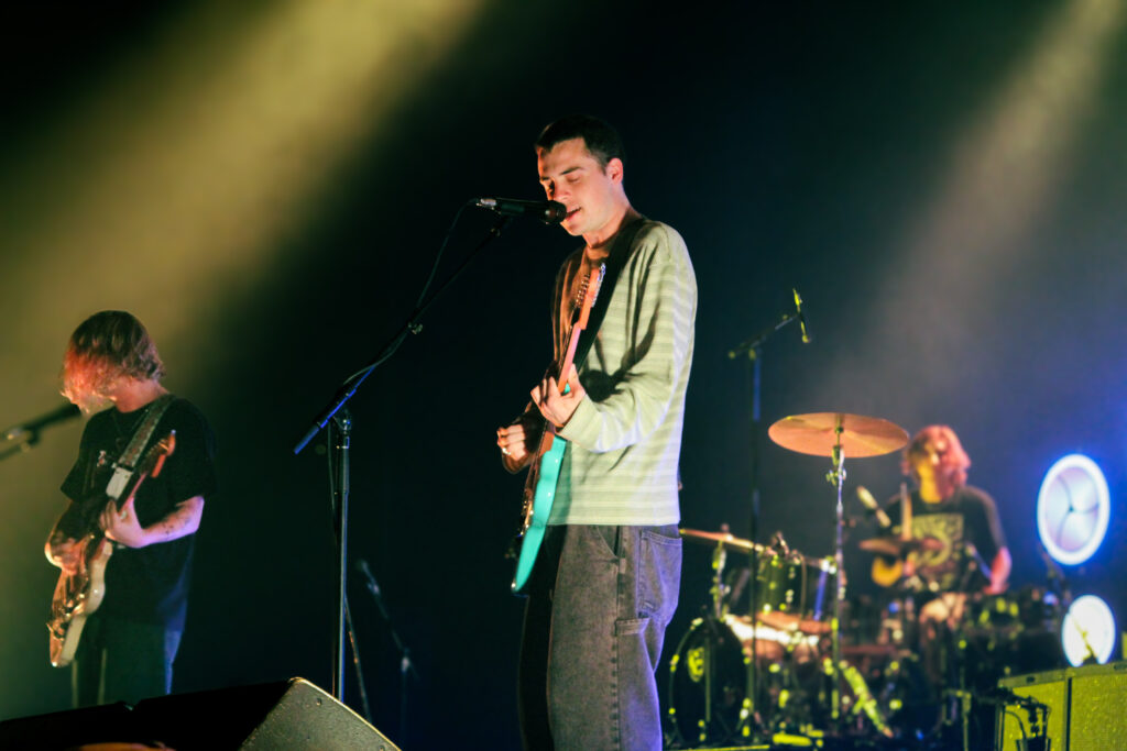 Guitar, bass, and drum members of a rock band on stage