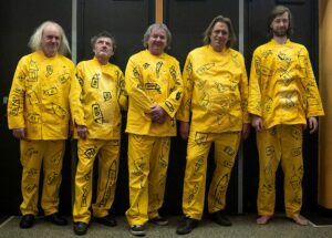 Band dressed in yellow standing in front of wall.