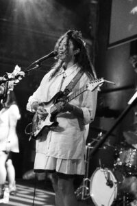 Shana Cleveland of La Luz singing into a microphone playing electric guitar