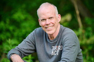 Press photo of Bill McKibben sitting outdoors, smiling