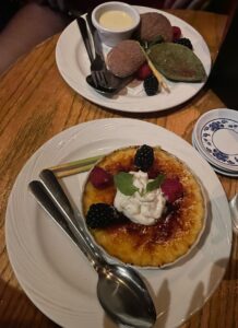 Two plates on a wooden table with pastries and creme brulee