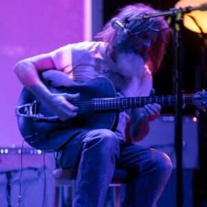 John Saint Pelvyn playing the guitar on stage.