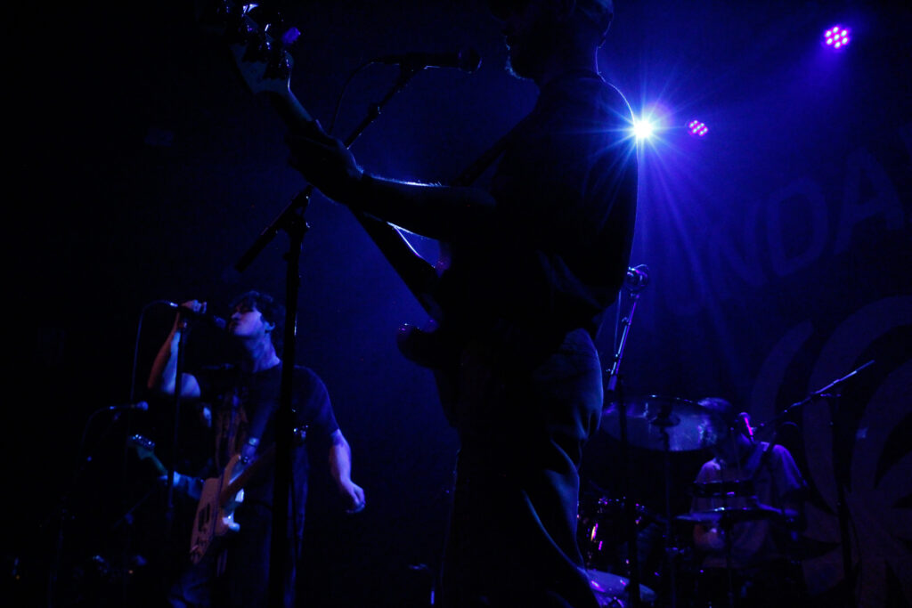 A rock band playing in dark blue stage lights