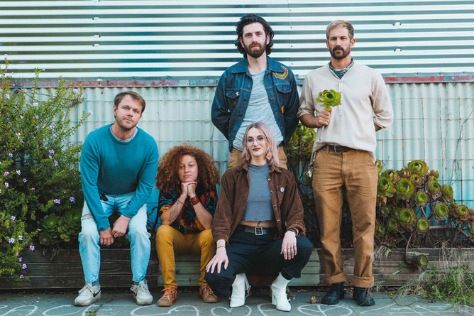 Five members of the rock band Mount Saint Elias standing and kneeling on a tree trunk