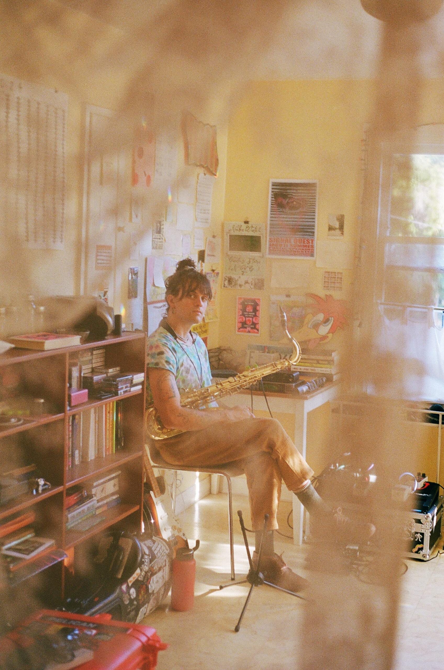 Cole Pulice sitting with a saxophone on their lap in a decorated room