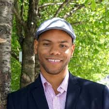 Headshot of Dr. Stephen Richmond wearing a dress shirt, jacket, and hat in front of trees