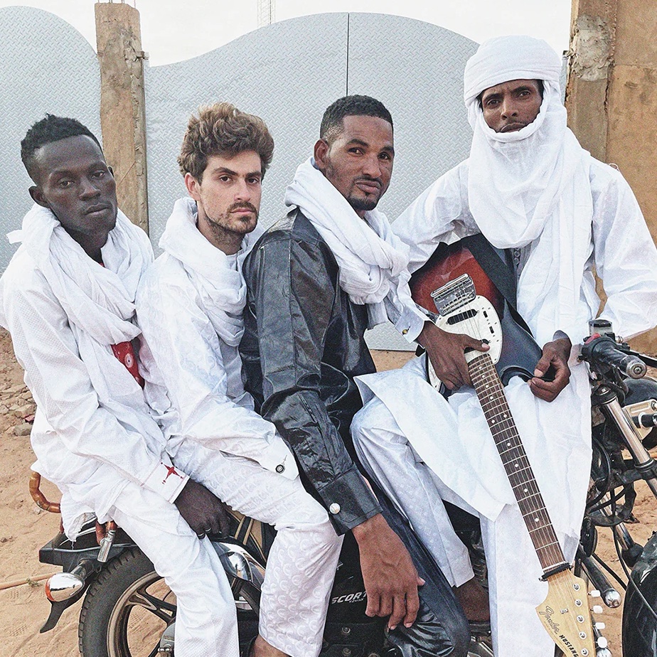 Mdou Moctar group sitting on a motorcycle together.