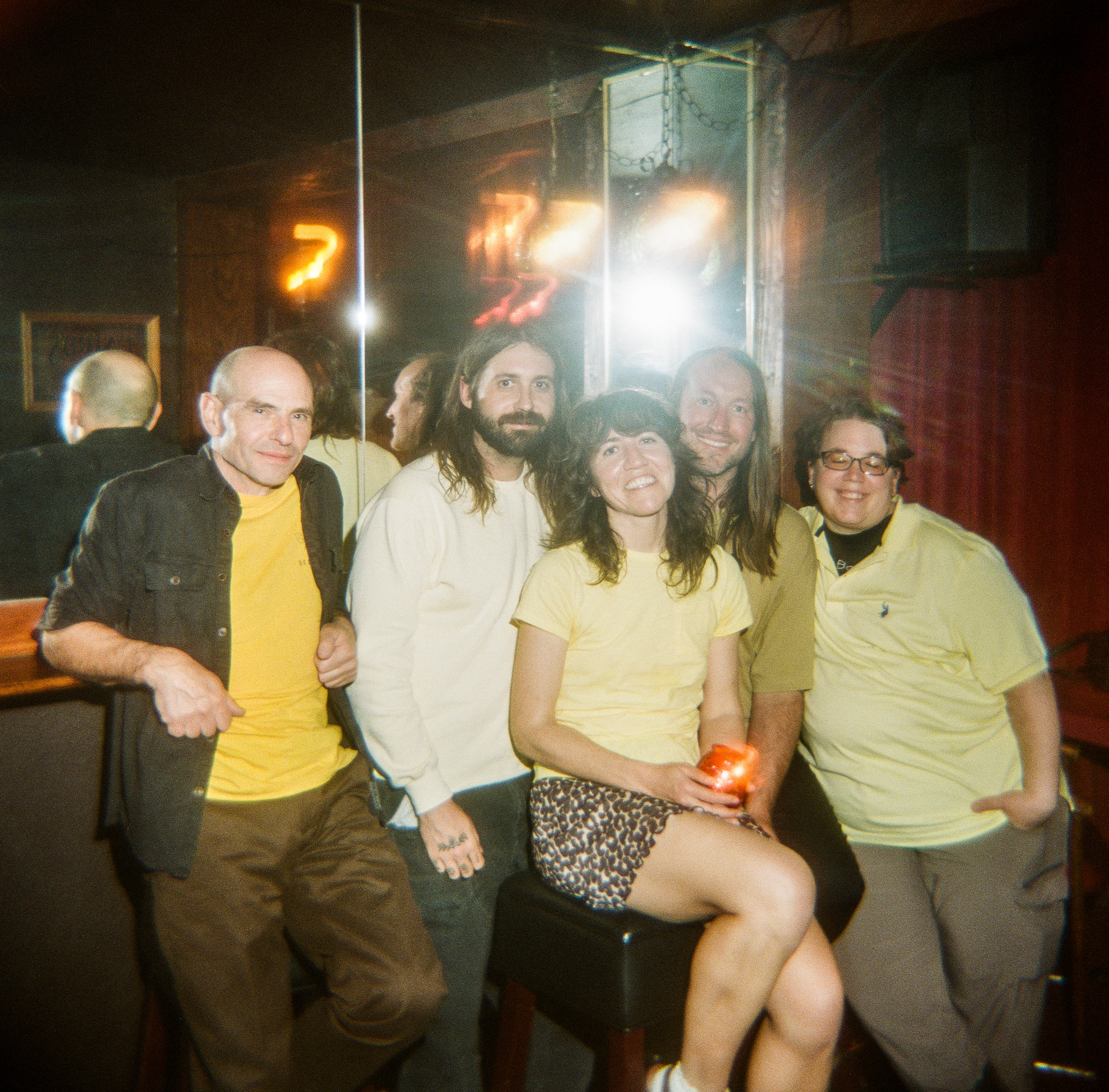 Quintet Eggcorn all wearing shades of yellow in a room with heavy lens flare